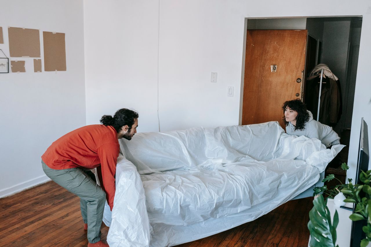 services-01 A couple collaboratively lifting a couch while moving into a new apartment.